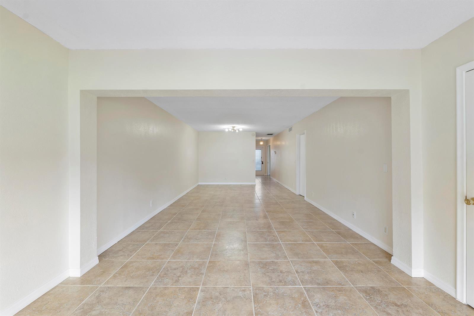 An empty, long room with beige tile flooring and light-colored walls — 1020 Citrus Way # 101, Delray Beach FL 33445, DELRAY BEACH, FL