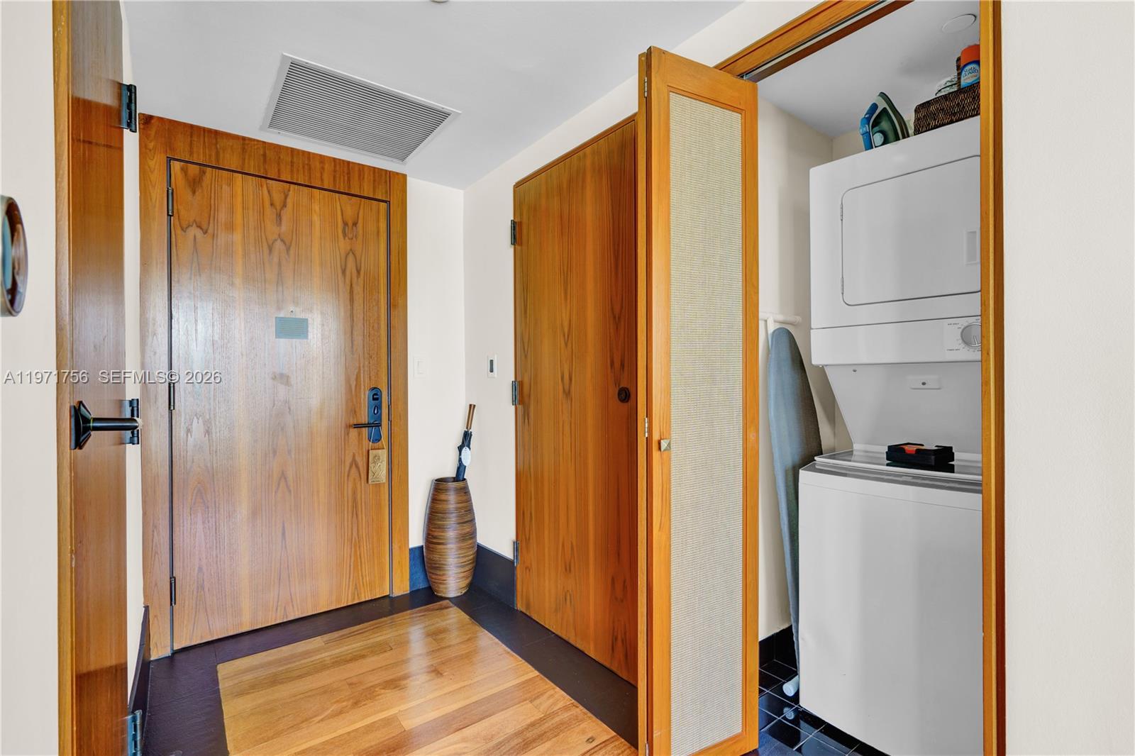 A hallway features wood doors, a wood floor inlay, and a closet with a stacked washer-dryer — 101 20th St # 1805, Miami Beach FL 33139, MIAMI BEACH, FL