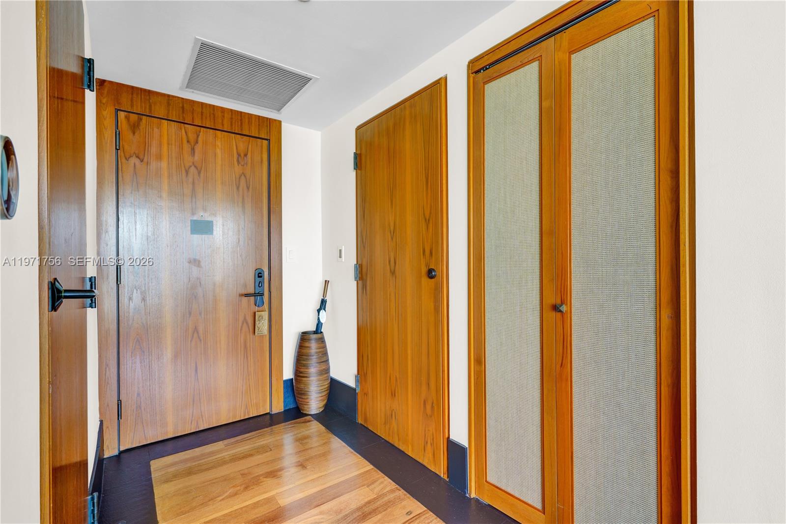 An entryway features wood-paneled doors, a textured closet, and dark flooring with a wood inlay — 101 20th St # 1805, Miami Beach FL 33139, MIAMI BEACH, FL