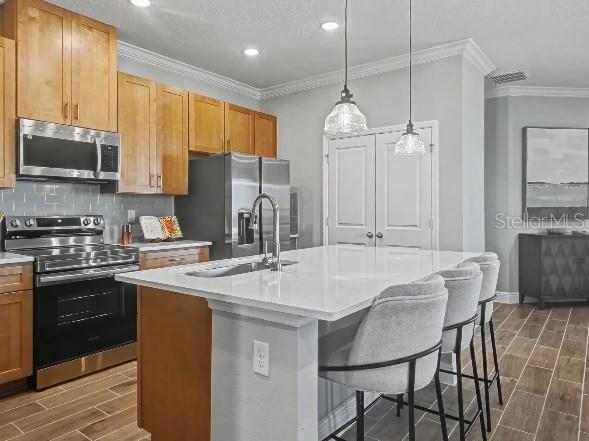 A kitchen features light wood cabinets, stainless steel appliances, a quartz island, and tile flooring — 898 BUCKEYE DRIVE, LADY LAKE, FL