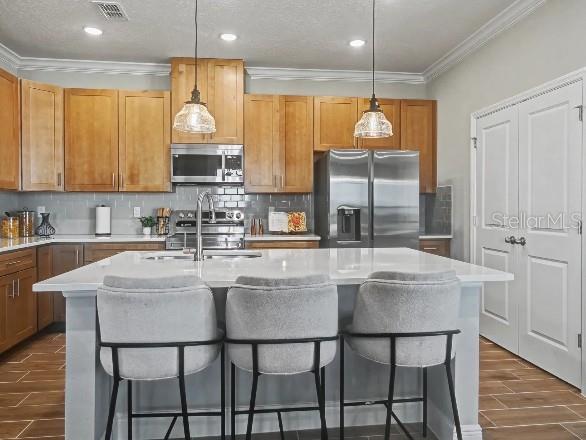 A kitchen features light wood cabinets, a white island with three stools, and stainless appliances — 898 BUCKEYE DRIVE, LADY LAKE, FL