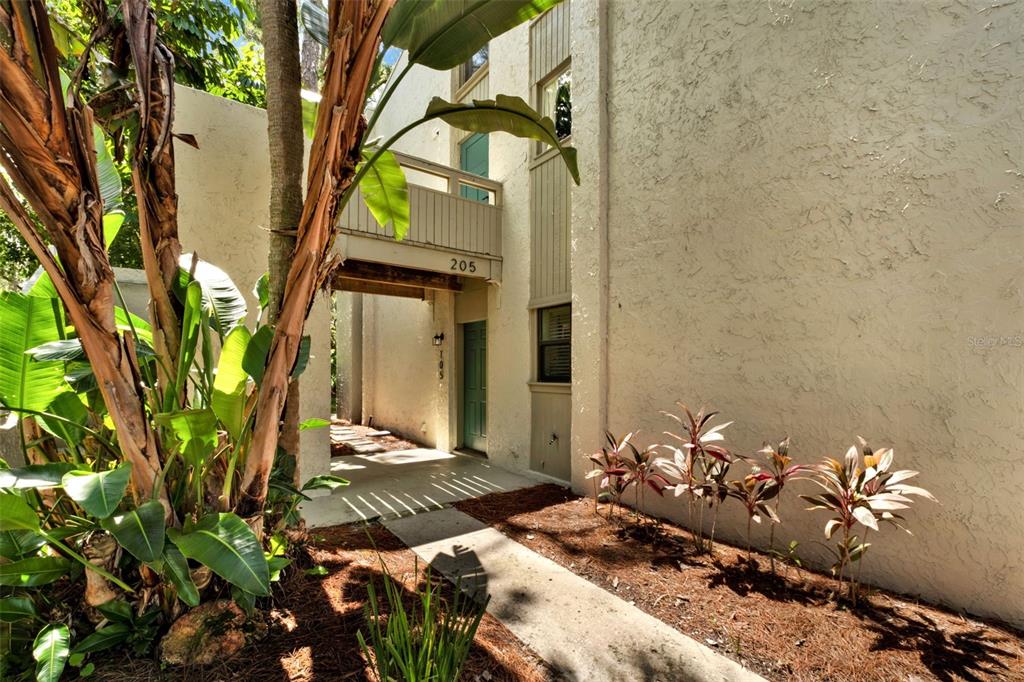 A wooden pergola covers a ground-level deck next to a tan building with a walkway — 105 FAIRWAY DRIVE, LONGWOOD, FL