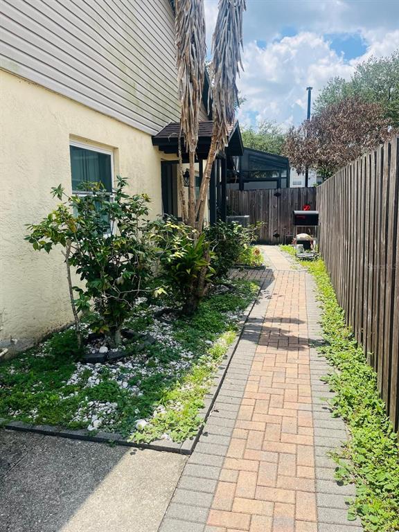 A brick walkway leads along the side of a house past a garden and wooden fence — 5424 SERENE LANE, ORLANDO, FL