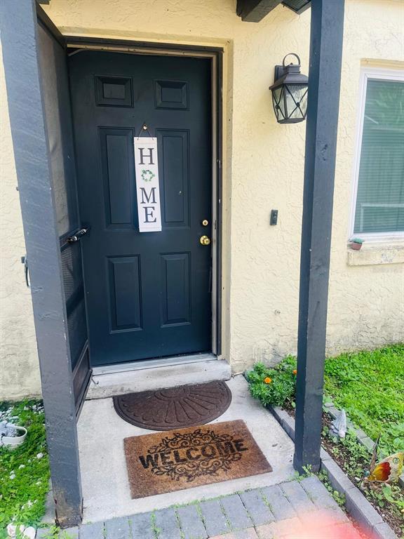A dark blue front door with a hanging sign sits under a porch light — 5424 SERENE LANE, ORLANDO, FL