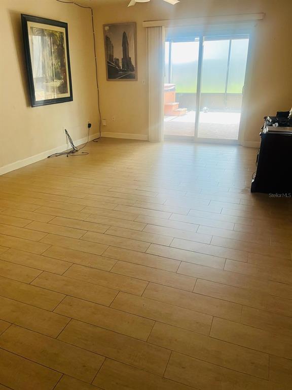 A living room with light wood-look tile flooring, two framed pictures, and a sliding glass door — 5424 SERENE LANE, ORLANDO, FL