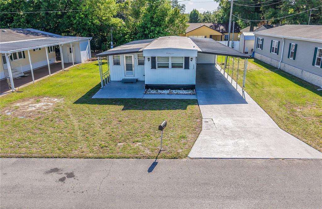 A white mobile home features a concrete driveway, a carport, and a small front yard — 5330 BETMAR DRIVE, ZEPHYRHILLS, FL