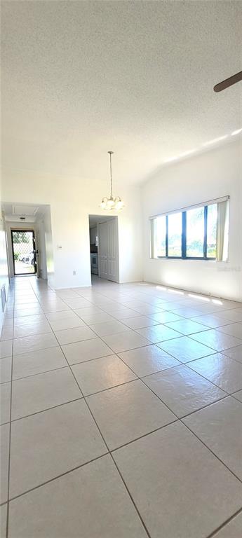 A bright, tiled living area features a dining light fixture and a large window — 5716 12TH AVENUE W UNIT 5716, BRADENTON, FL