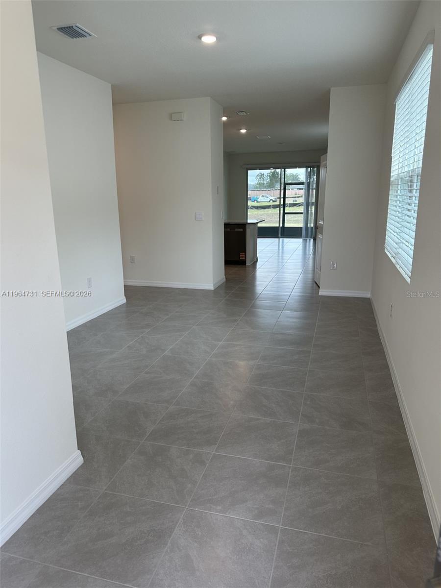 An interior view shows a tiled room leading to a kitchen and a screened patio — 4078 NW 44 CIR # 0, Ocala FL 34482, OCALA, FL