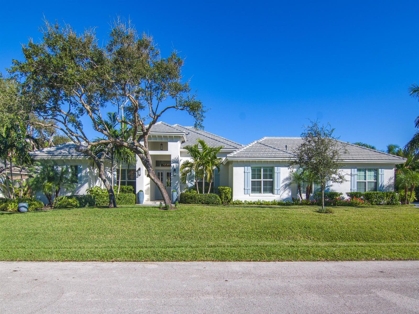 A single-story house with a white stucco exterior, grey tile roof, and blue shutters — VERO BEACH, FL