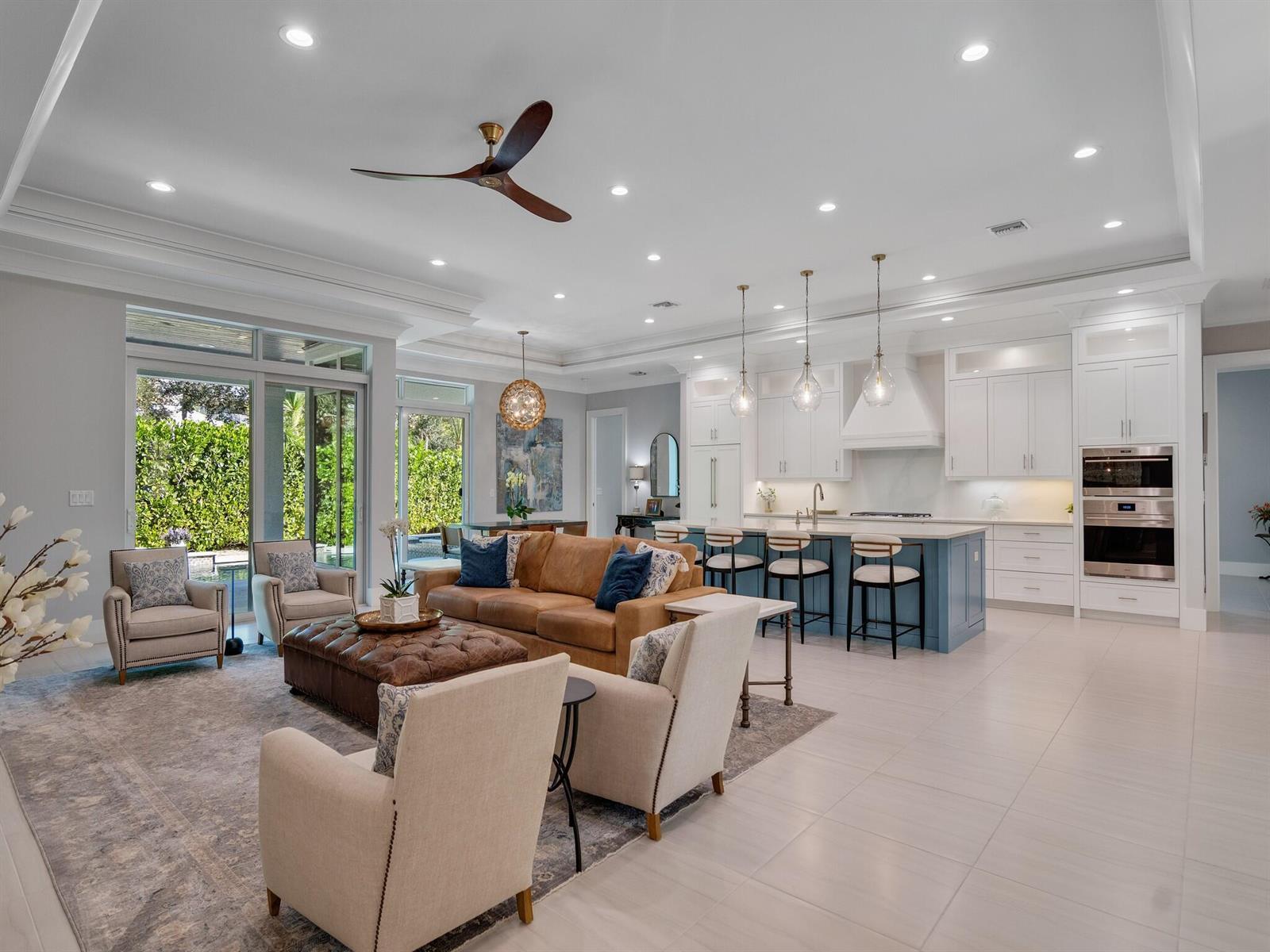 An open-concept living room and kitchen with white cabinetry, a blue island, and leather furniture — VERO BEACH, FL