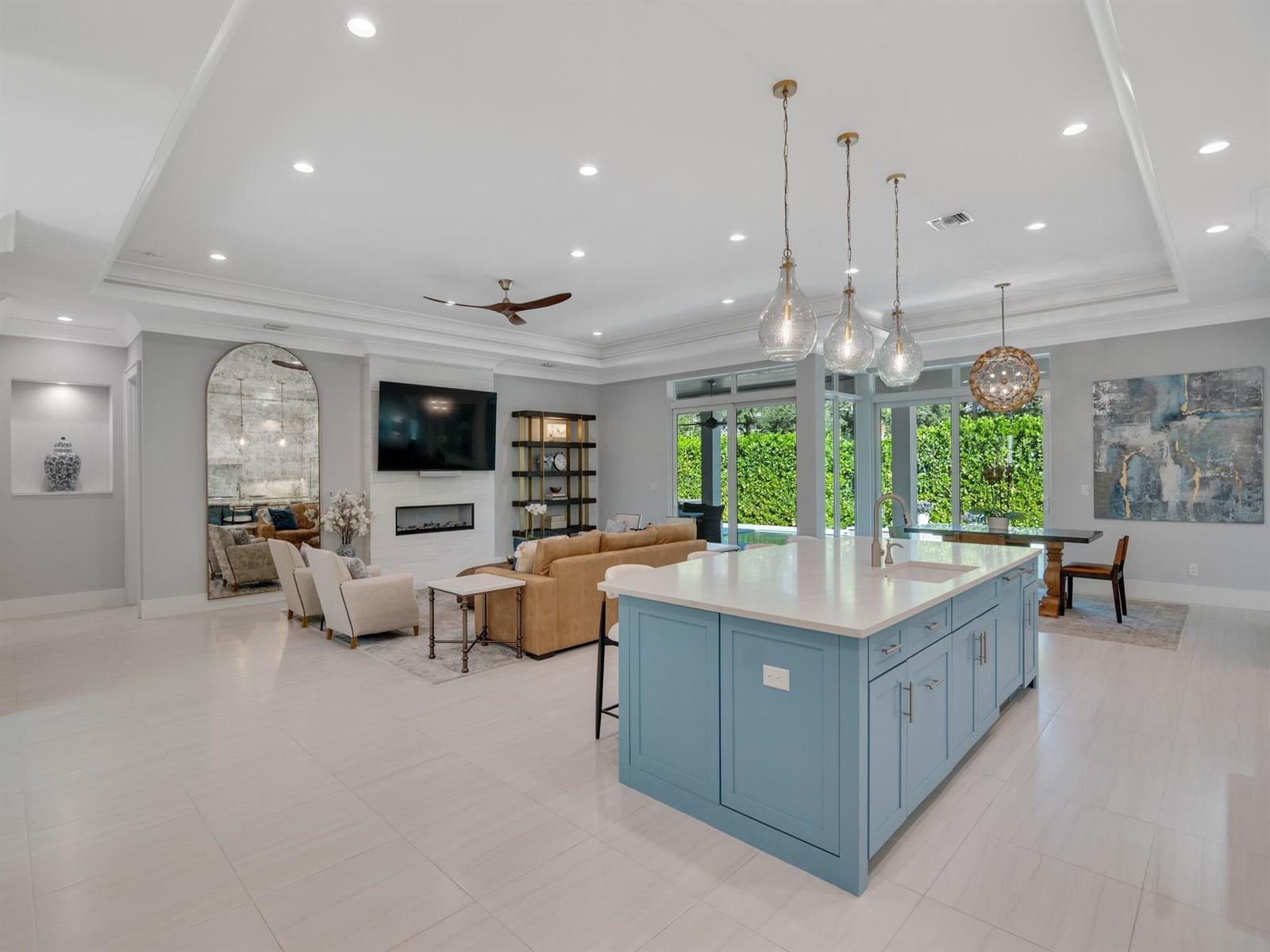 An open-concept living room and kitchen featuring a blue island and a fireplace — VERO BEACH, FL