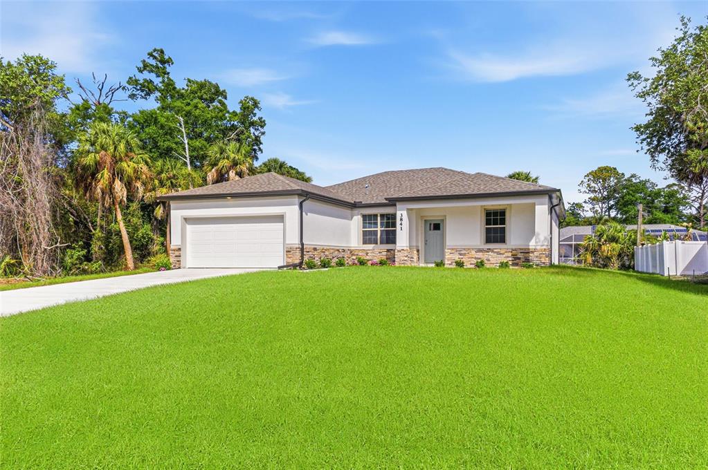 A single-story house with a white garage, stone accents, and a green lawn — 3841 S CRANBERRY BOULEVARD, NORTH PORT, FL