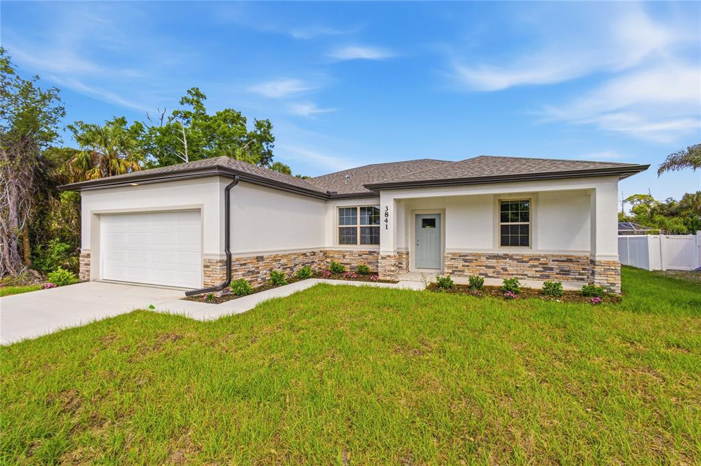 A single-story house features a white stucco exterior, stone veneer accents, and a two-car garage — 3841 S CRANBERRY BOULEVARD, NORTH PORT, FL