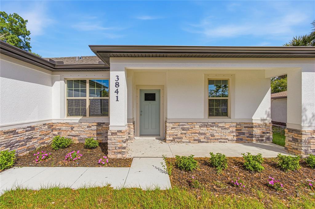 The exterior of a single-story house features a light blue front door and stone siding — 3841 S CRANBERRY BOULEVARD, NORTH PORT, FL