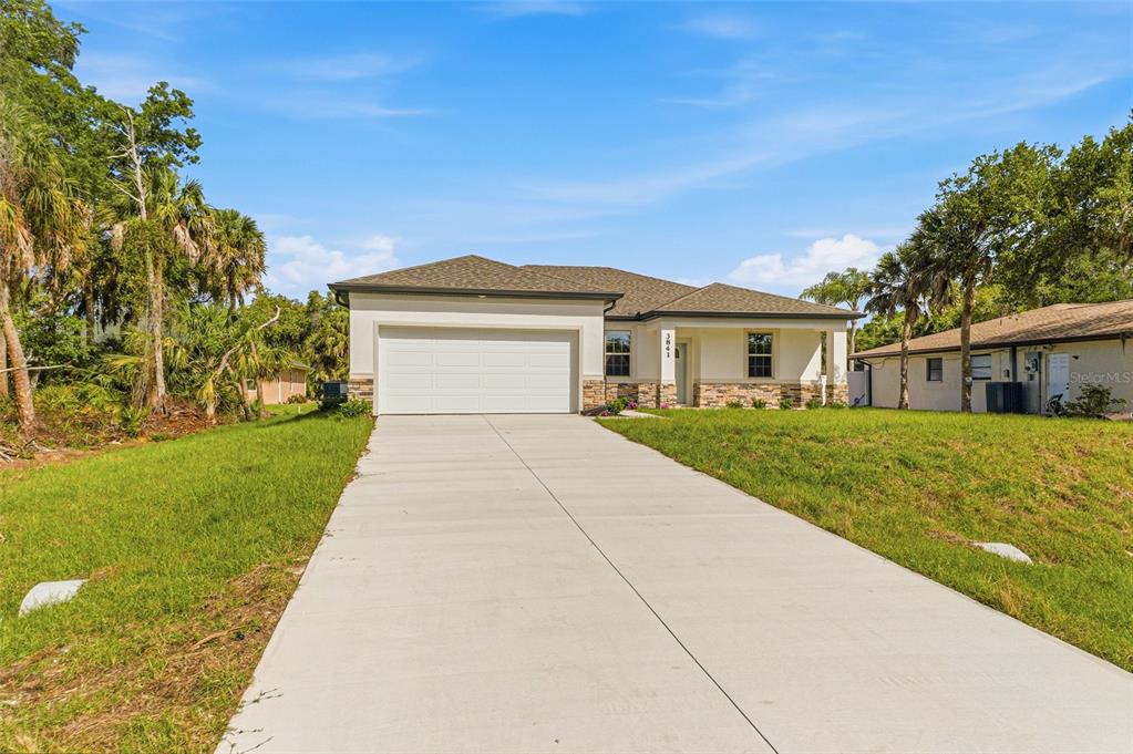 A single-story house with a white garage, stone accents, and a concrete driveway — 3841 S CRANBERRY BOULEVARD, NORTH PORT, FL