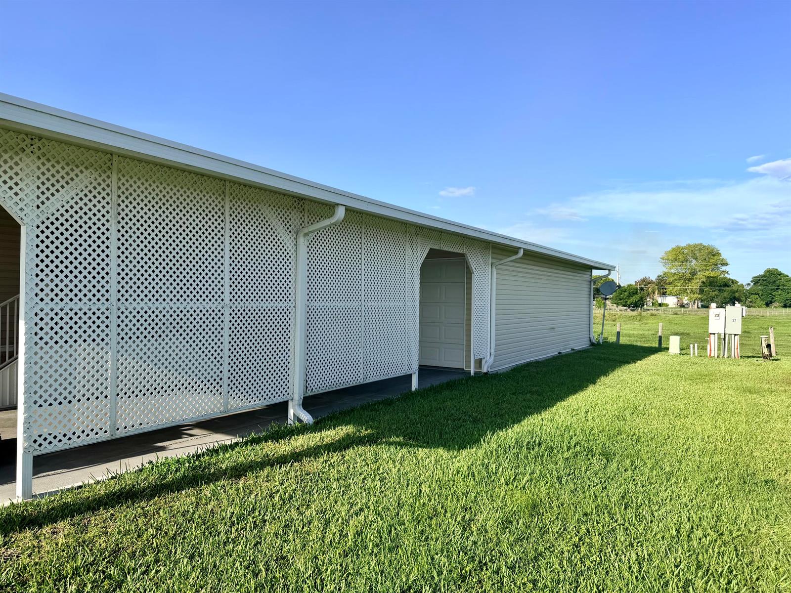 A side view of a building exterior featuring white lattice screening and a garage door — 1601 SE Us Highway 441 # 22, Okeechobee FL 34974, OKEECHOBEE, FL