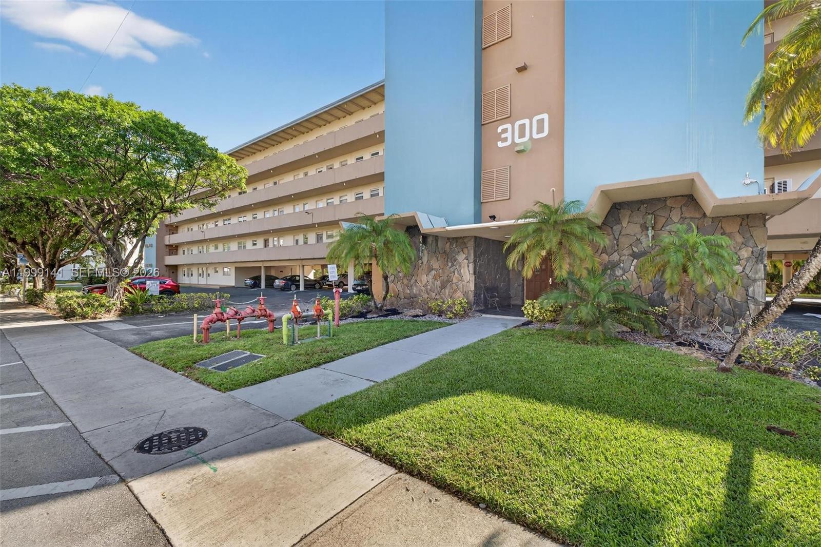 Exterior view of a multi-story apartment building with a stone facade and fire department connections — 300 NE 14th Ave # 505, Hallandale Beach FL 33009, HALLANDALE BEACH, FL