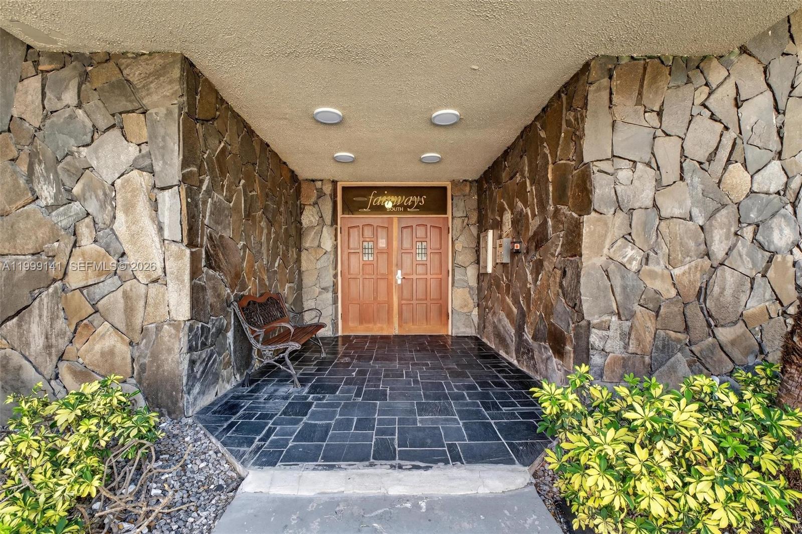 The entrance to a building features stone walls, a tiled floor, and double wooden doors — 300 NE 14th Ave # 505, Hallandale Beach FL 33009, HALLANDALE BEACH, FL