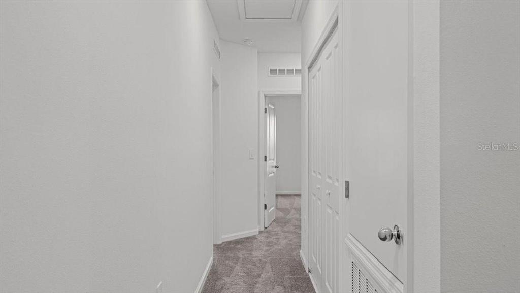A carpeted hallway features white walls, a closet with louvered doors, and an open doorway — 3302 LAURENT LOOP, DAVENPORT, FL