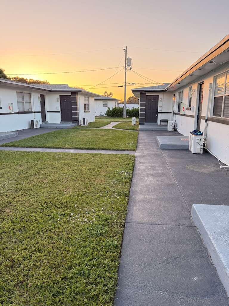 An exterior view of a residential apartment complex with a grassy courtyard and concrete walkways — 1885 40th Avenue Unit 4, Vero Beach FL 32960, VERO BEACH, FL