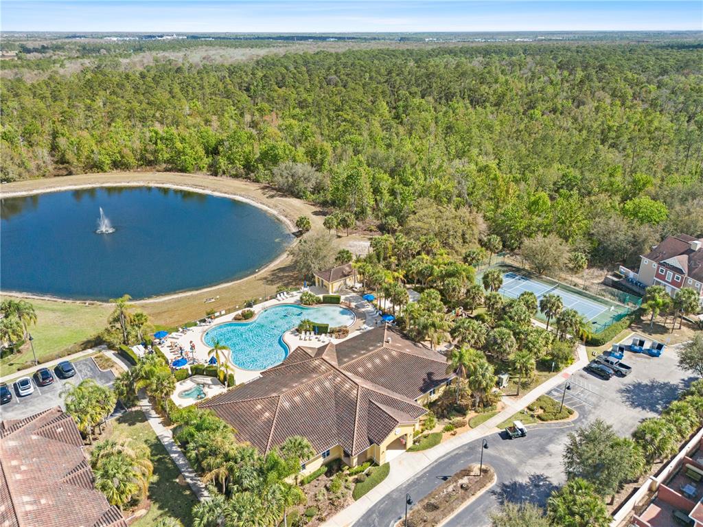An aerial view shows a community clubhouse with a pool, tennis court, and pond — 7519 BLISS WAY UNIT 7519, KISSIMMEE, FL