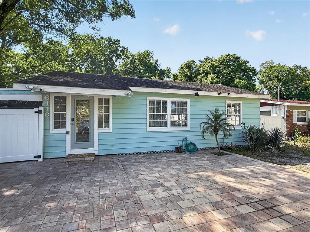 A light blue house with a paved patio and a white gate stands outside — 6416 N ORLEANS AVENUE, TAMPA, FL