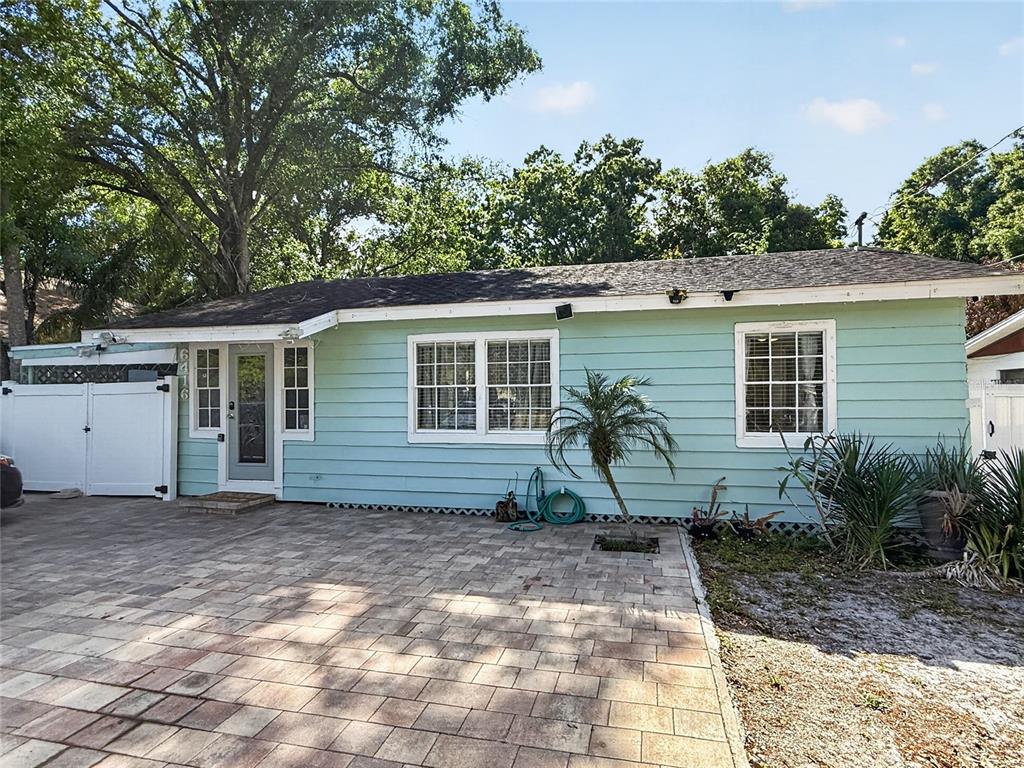 A light green house with white trim features a paved driveway and a small palm tree — 6416 N ORLEANS AVENUE, TAMPA, FL