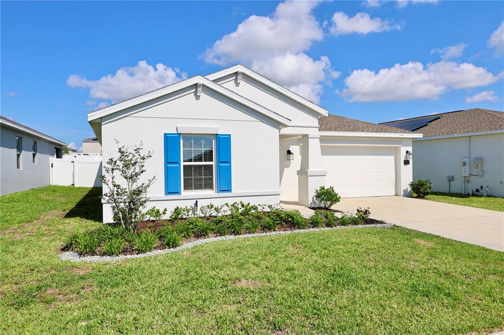 A white single-story house with blue shutters, a front lawn, and a concrete driveway — 965 LAUREL VIEW WAY, GROVELAND, FL