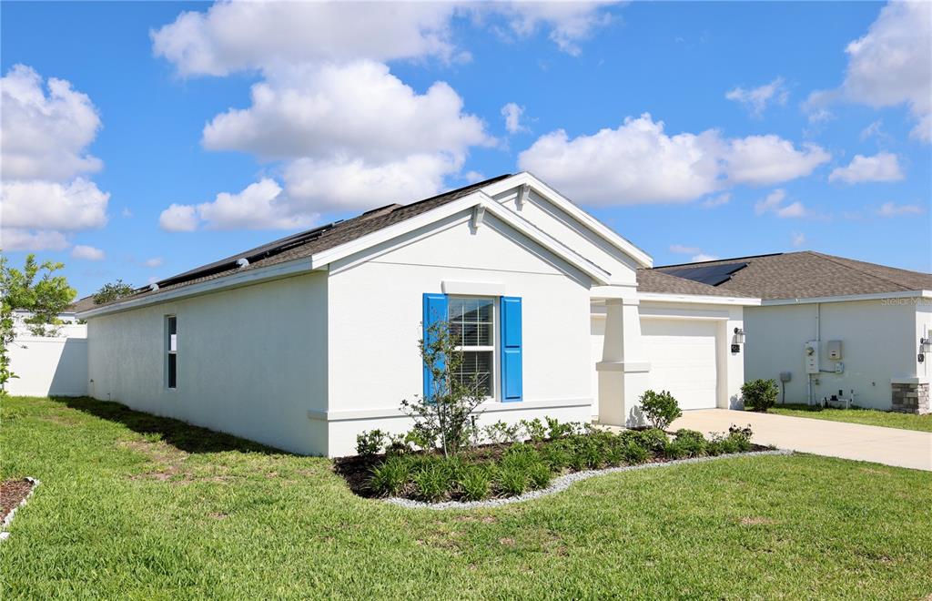 A white single-story house with blue shutters and a garage under a blue sky — 965 LAUREL VIEW WAY, GROVELAND, FL