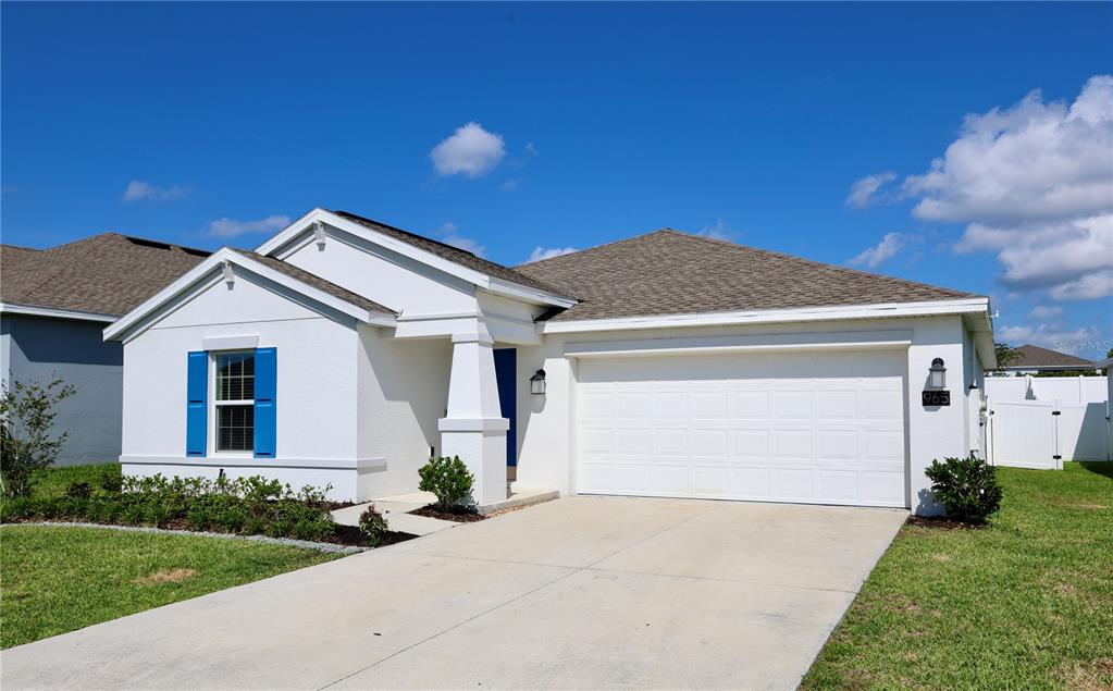 A white single-story house with a two-car garage and blue shutters under a blue sky — 965 LAUREL VIEW WAY, GROVELAND, FL