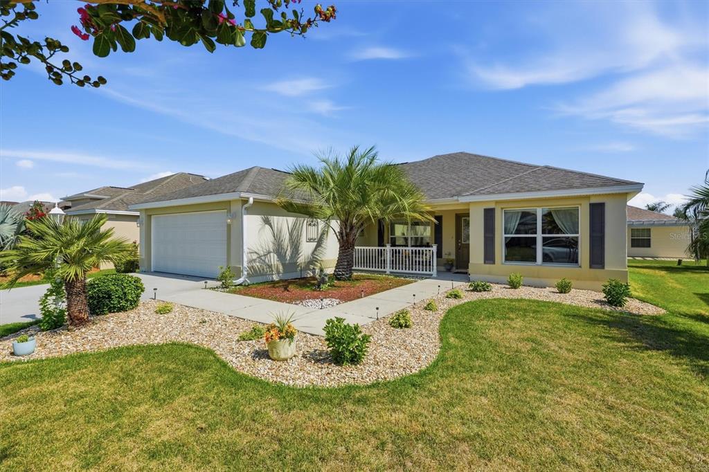 A single-story suburban house with a two-car garage, palm trees, and a landscaped front yard — 2007 YEARLING WAY, THE VILLAGES, FL