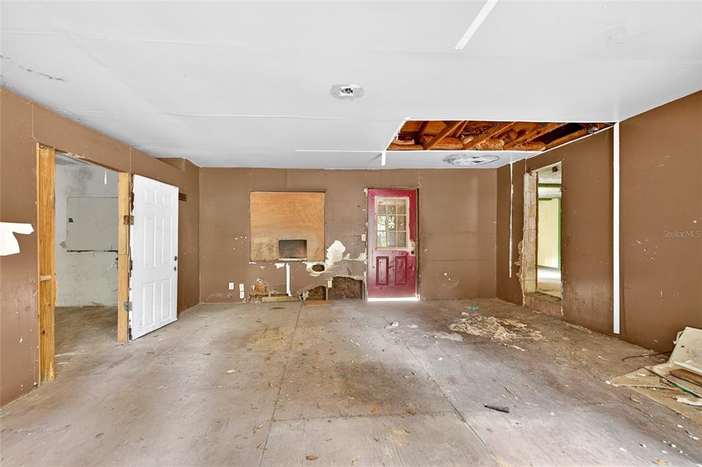 A room with brown walls, a damaged ceiling, and a red exterior door — 15176 NE 154TH LANE, FORT MC COY, FL