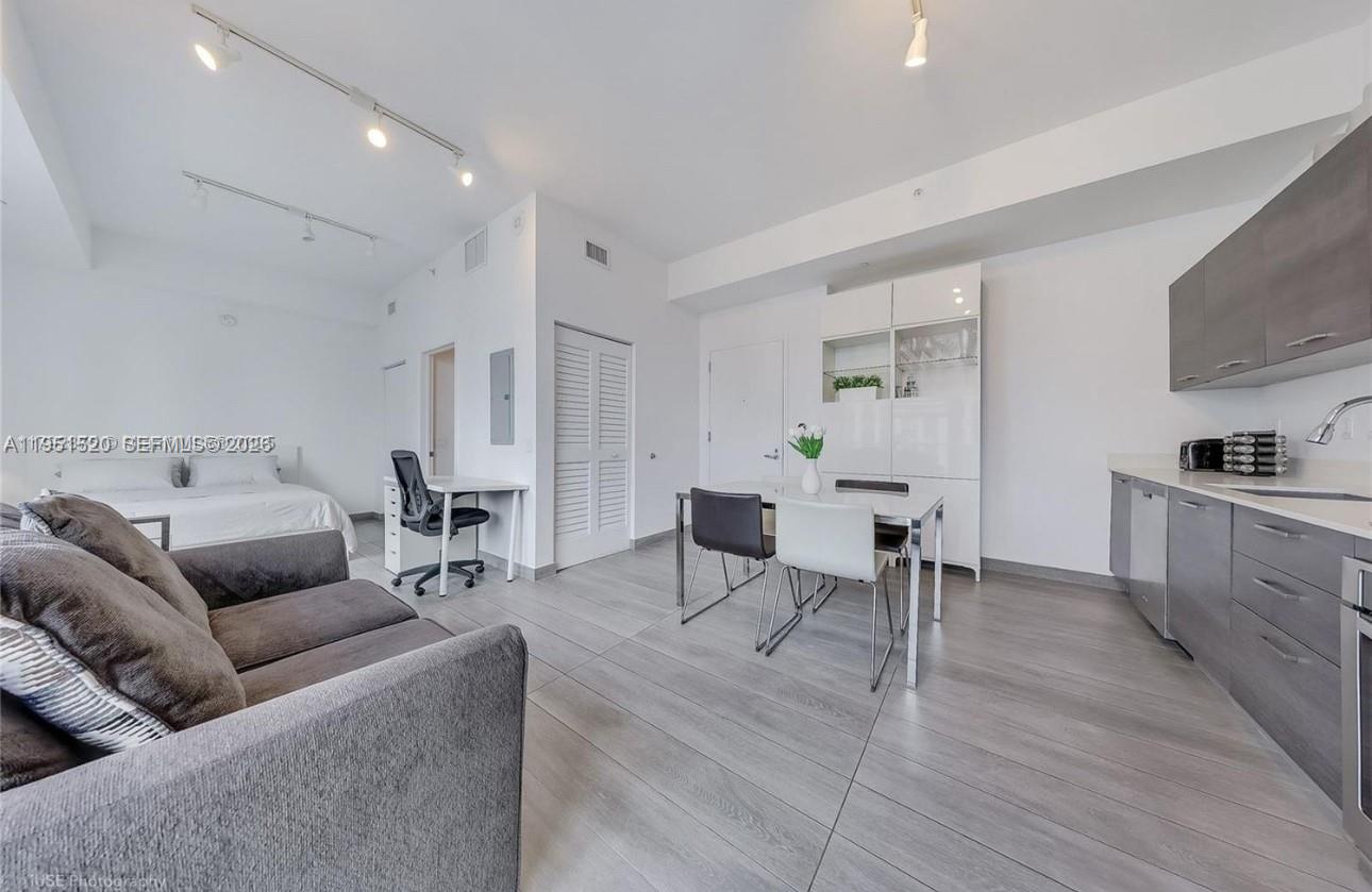 A studio apartment features a kitchen, dining area, desk, and bed on light wood flooring — 151 SE 1st St # 1706, Miami FL 33131, MIAMI, FL