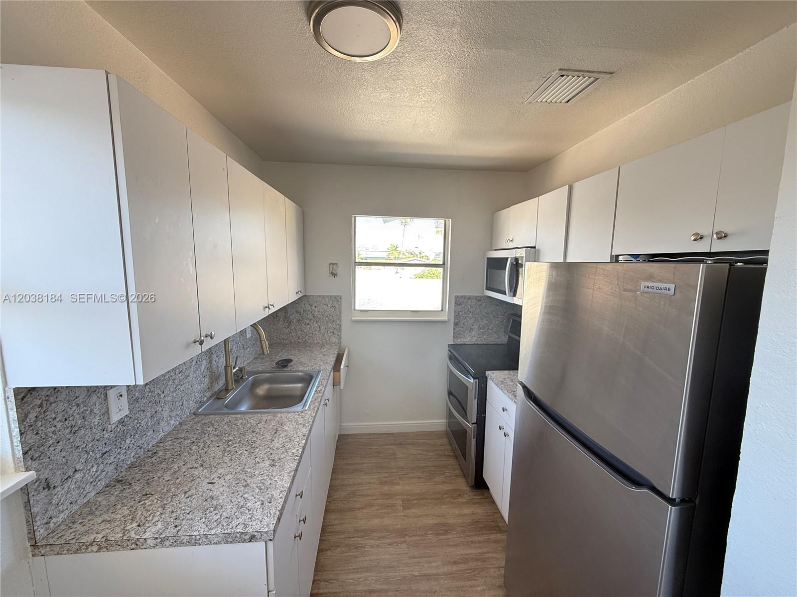 A galley kitchen features white cabinets, granite countertops, and stainless steel appliances — 236 SW 10th Ave # B, Miami FL 33130, MIAMI, FL