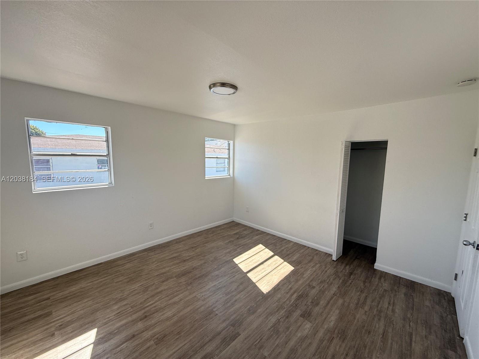An empty bedroom features white walls, wood-look flooring, two windows, and a small closet — 236 SW 10th Ave # B, Miami FL 33130, MIAMI, FL
