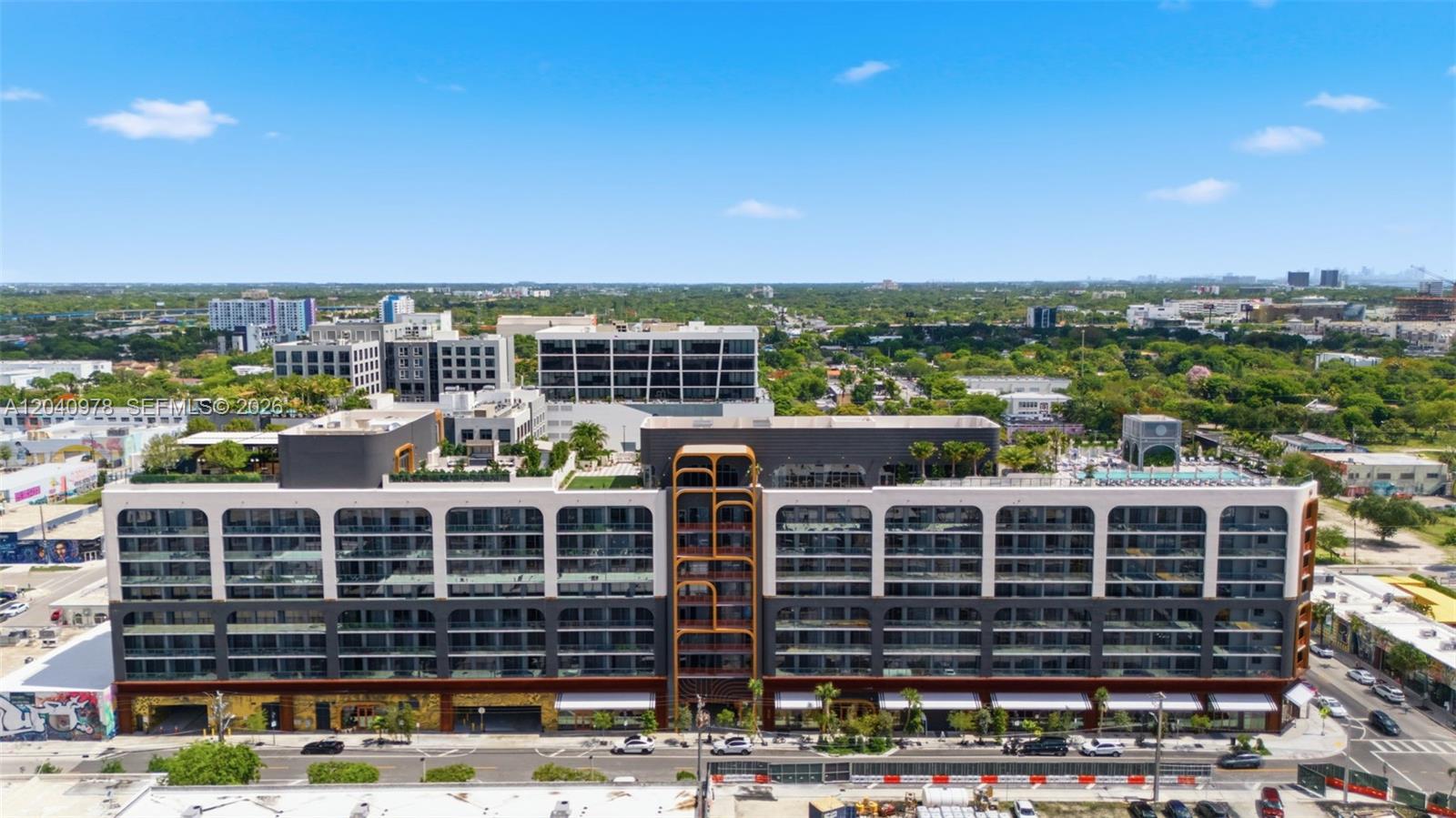 An aerial view shows a modern multi-story apartment building with a central gold-toned architectural feature — 2700 NW 2nd # 317, Miami FL 33127, MIAMI, FL