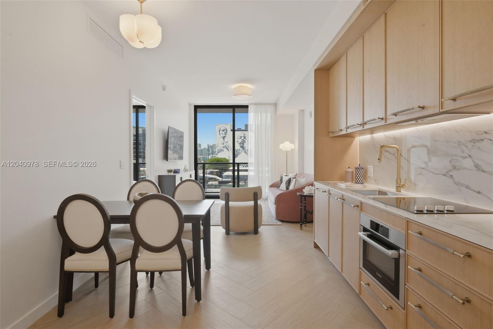A modern kitchen and dining area features light wood cabinetry, marble countertops, and herringbone flooring — 2700 NW 2nd # 317, Miami FL 33127, MIAMI, FL
