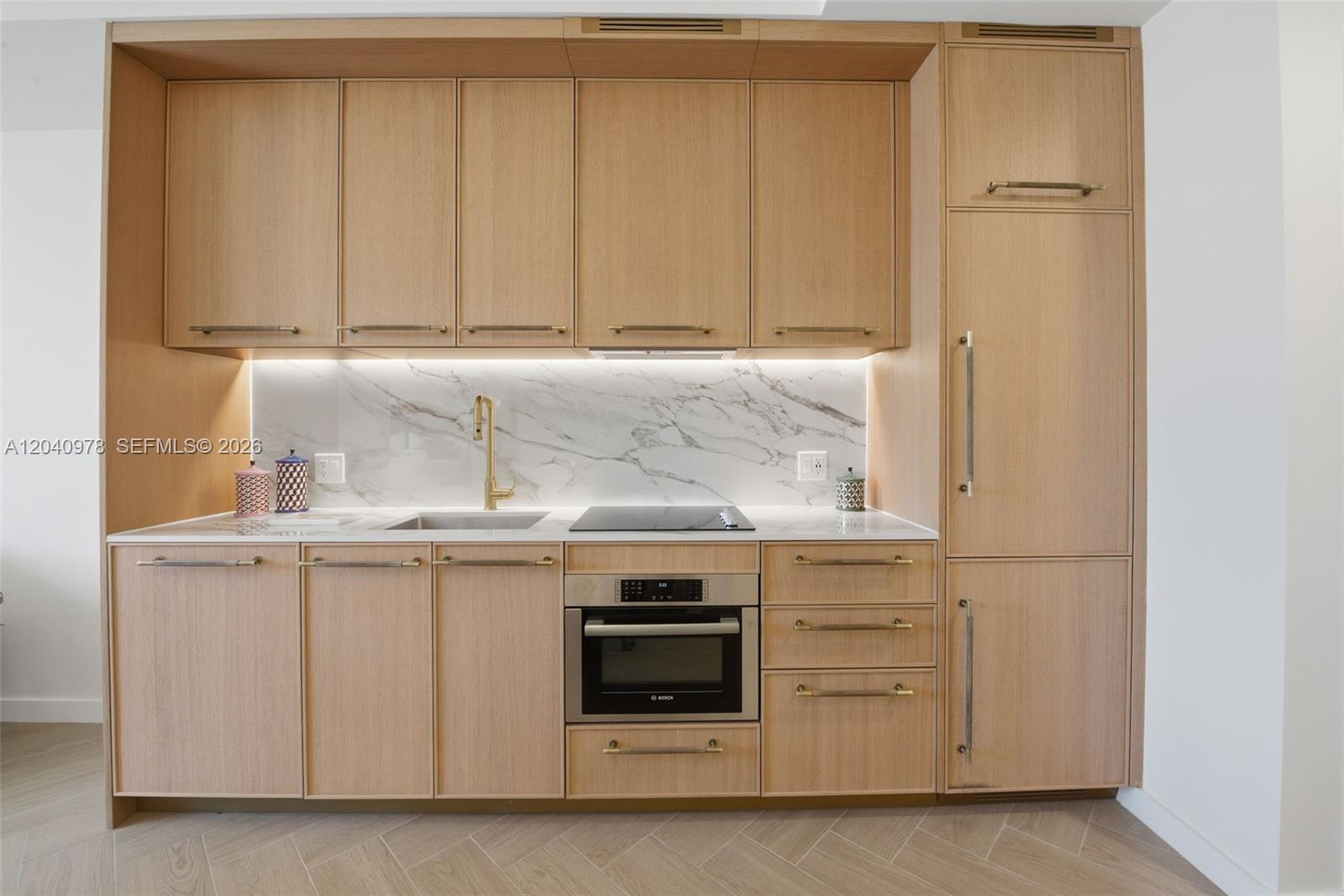 A modern kitchen features light wood cabinetry, a marble backsplash, and integrated stainless steel appliances — 2700 NW 2nd # 317, Miami FL 33127, MIAMI, FL