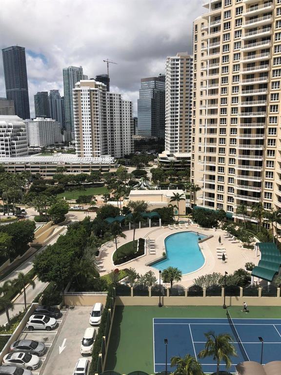 A high-angle view shows a swimming pool, tennis court, and parking area surrounded by city skyscrapers — 848 Brickell Key Drive # 1505, Miami FL 33131, MIAMI, FL