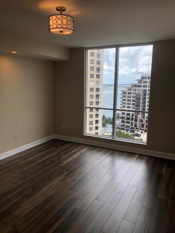 An empty room with dark wood-look flooring, a patterned ceiling light, and floor-to-ceiling windows — 848 Brickell Key Drive # 1505, Miami FL 33131, MIAMI, FL