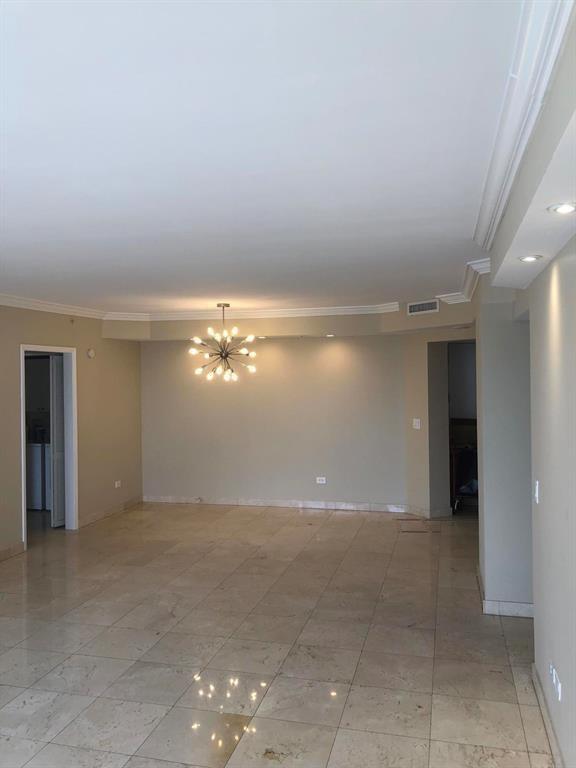 An empty room with beige walls, tile flooring, and a modern sputnik-style chandelier — 848 Brickell Key Drive # 1505, Miami FL 33131, MIAMI, FL