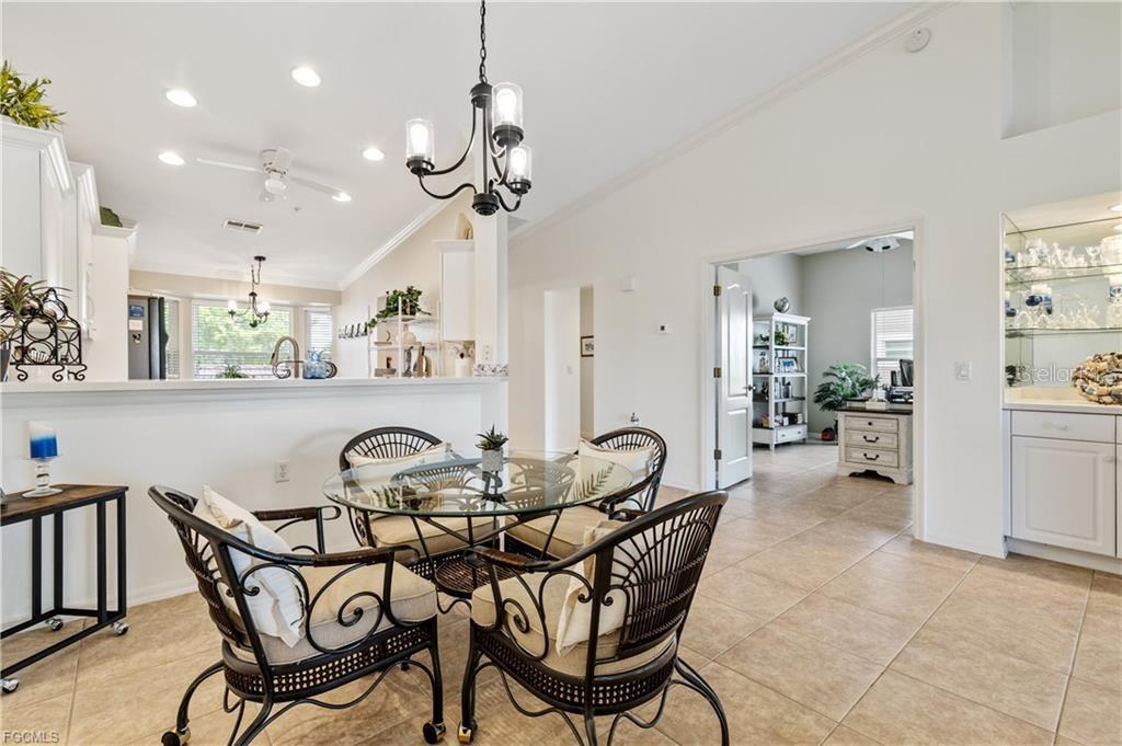 A dining area with a glass table and wicker chairs sits before an open kitchen — 10420 WINE PALM ROAD UNIT 5421, FORT MYERS, FL