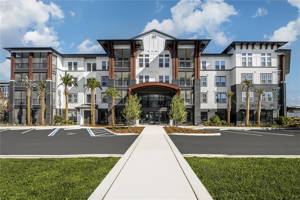 A multi-story apartment building with a central entrance, dark accents, and palm trees in front — 20191 SABAL PALM COURT UNIT B2, LAND O LAKES, FL