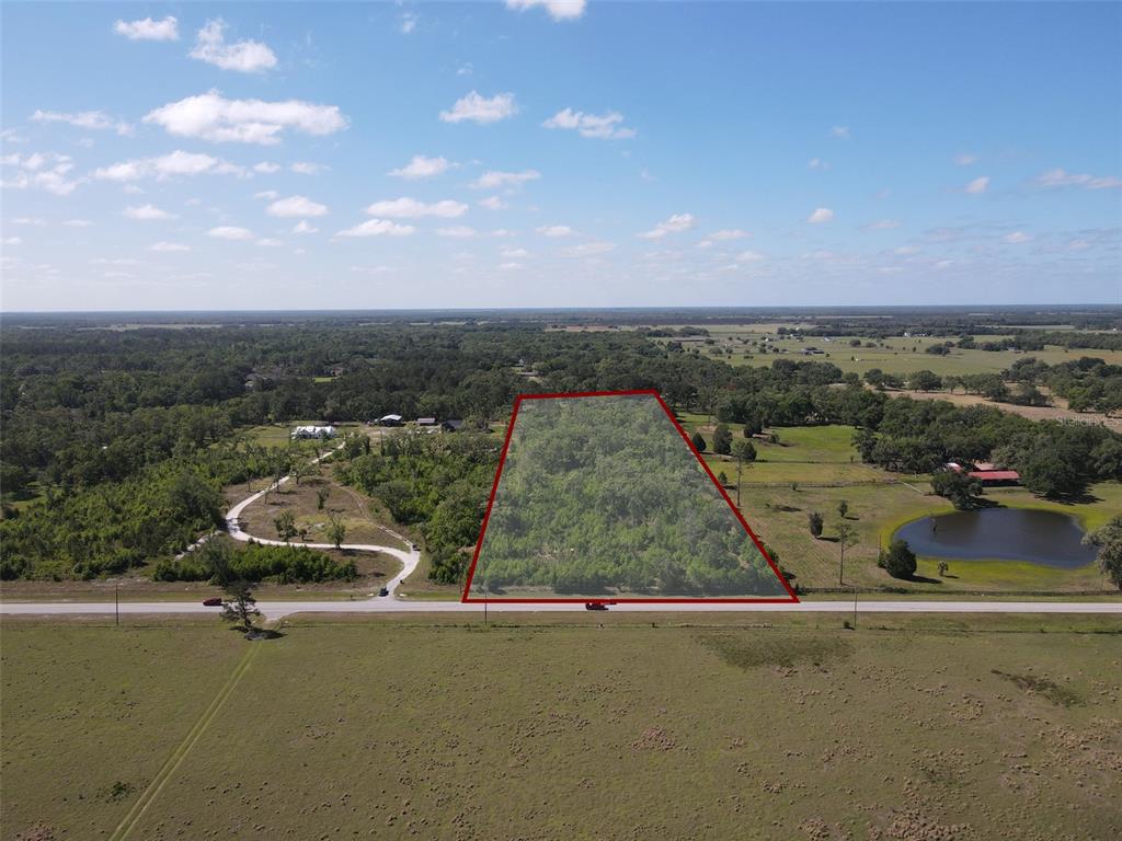 An aerial view shows a rectangular, wooded plot of land outlined in red along a road — AYERS ROAD, BROOKSVILLE, FL