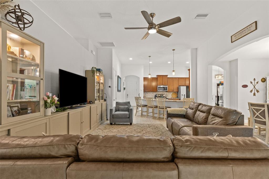 A living room with a brown leather sofa faces a built-in media center and kitchen — 107 ELINA SKY DRIVE, SEFFNER, FL