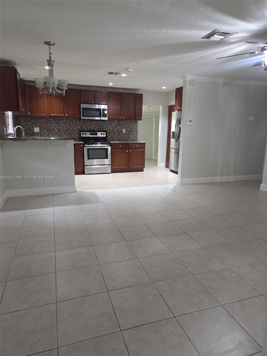 A kitchen with dark wood cabinets, stainless steel appliances, and tile flooring — 6118 Royal Palm Blvd, Margate FL 33063, MARGATE, FL