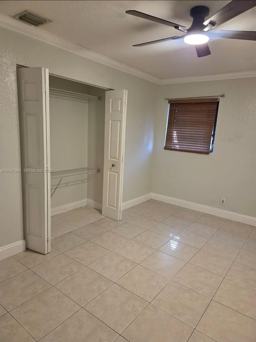 A bedroom features light-colored tile flooring, a ceiling fan, and an open closet — 6118 Royal Palm Blvd, Margate FL 33063, MARGATE, FL