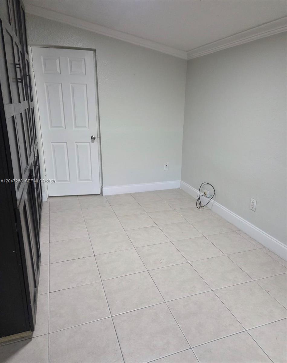 A room with light-colored tile flooring, a white door, and a dark cabinet unit — 6118 Royal Palm Blvd, Margate FL 33063, MARGATE, FL
