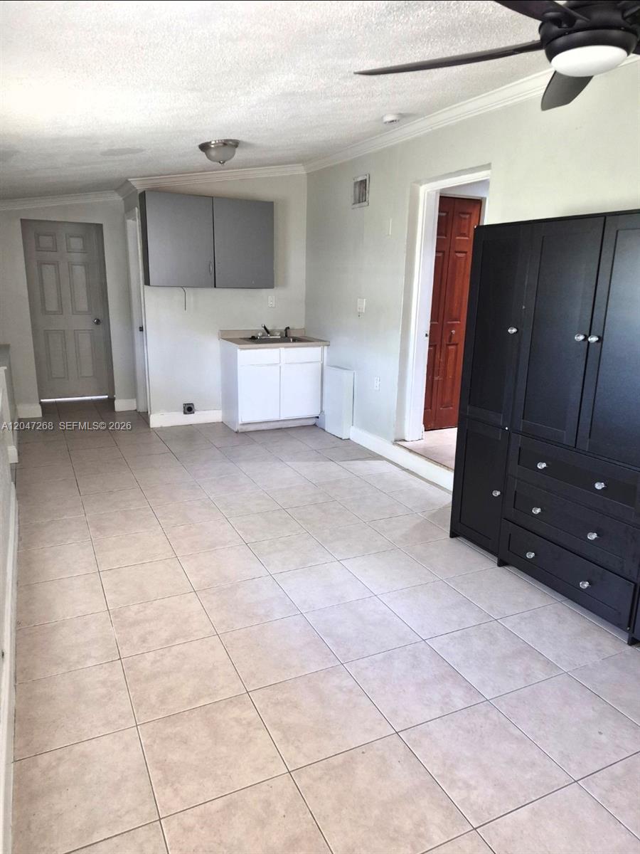 This room features tile flooring, a small kitchenette with upper cabinets, and a black wardrobe — 6118 Royal Palm Blvd, Margate FL 33063, MARGATE, FL