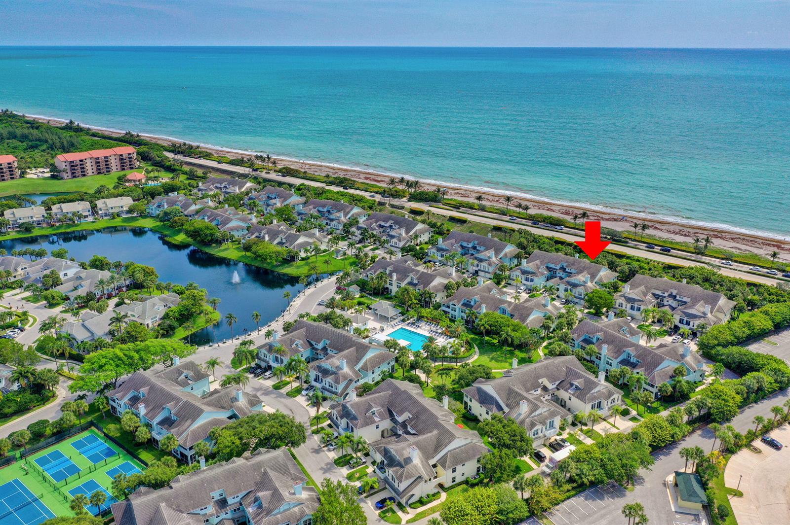 An aerial view shows a coastal residential community with a pool, tennis courts, and lake — 207 Mainsail Circle, Jupiter FL 33477, JUPITER, FL